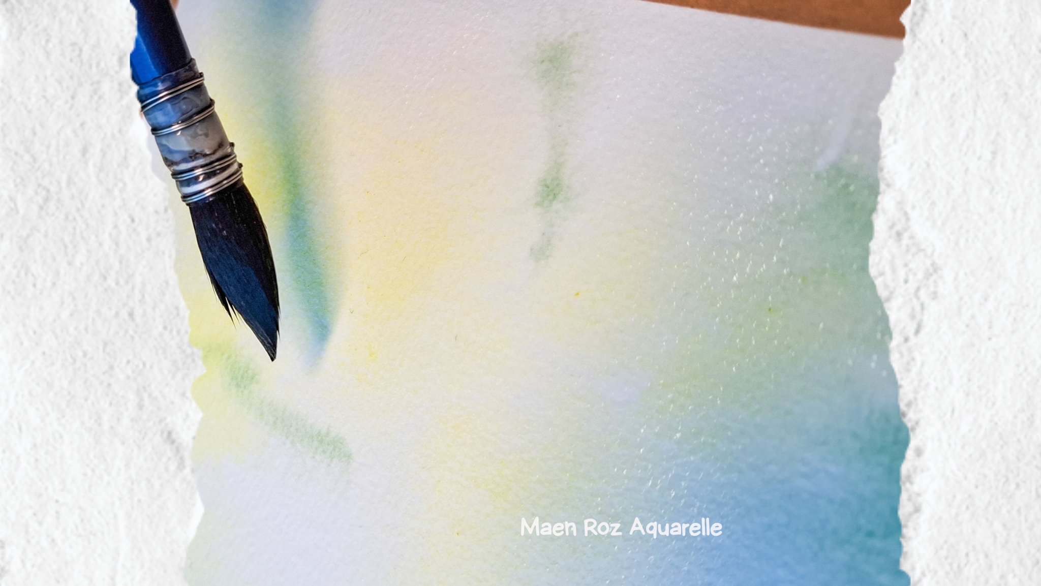 Lavis d’aquarelle en cours de séchage avec un pinceau posé sur le papier