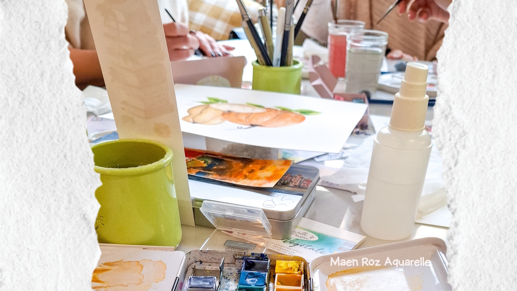 Ambiance d’atelier d’aquarelle avec palettes, pinceaux et participants en train de peindre