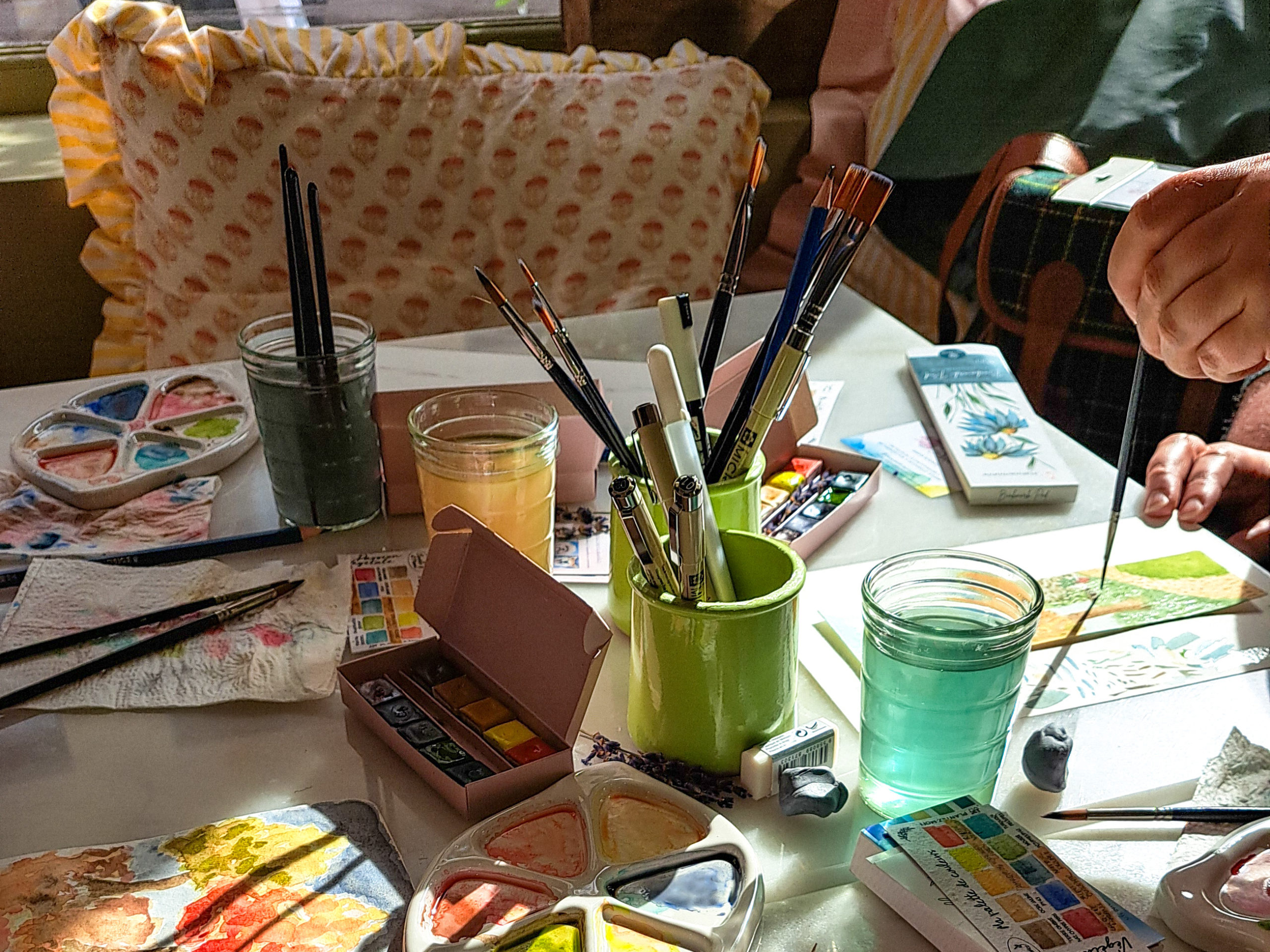 Mains tenant un pinceau lors d’un atelier d’aquarelle en petit groupe